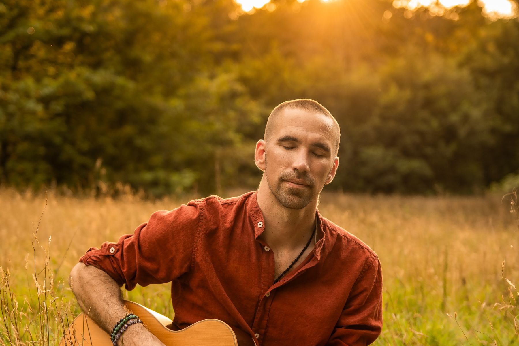 Jorn Ayan with a guitar in an open field