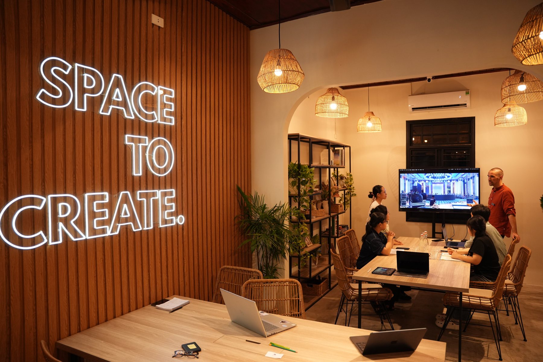 A co-working space set up for a workshop, with a lit 'Space to Create' wall sign